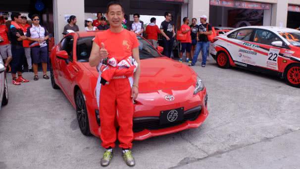 Celebrities at 2017 Toyota Vios Cup A man posing for a photo in front of a racing car