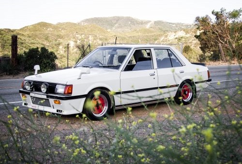 Whenever you hear the noise of clunks, surely, the Mitsubishi is coming. Angular front of a white Misubishi Lancer (Box type)