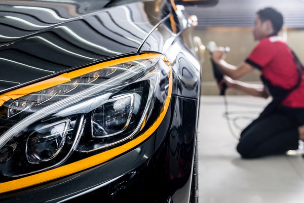 a mechanic cleaning car exterior