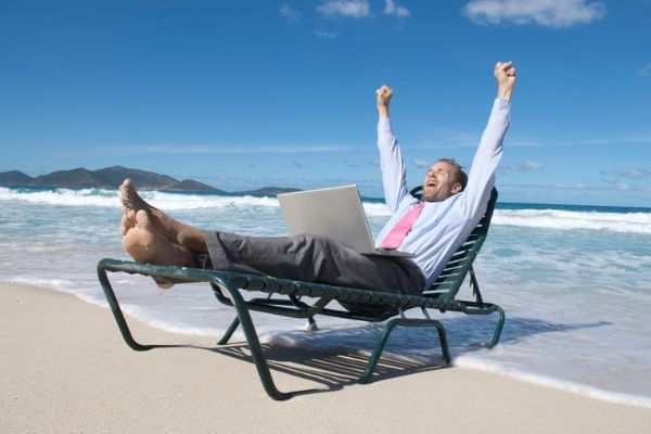 A picture of a man working while at the beach.