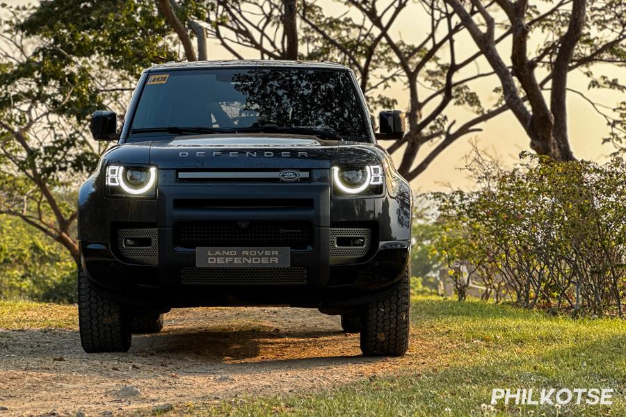 The Defender 110 parked near some trees.