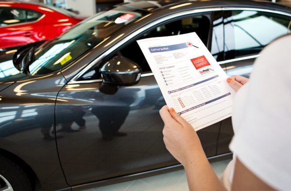 It’s essential to require a vehicle history report unless you are buying the car from someone you trust a woman holding a vehicle history report