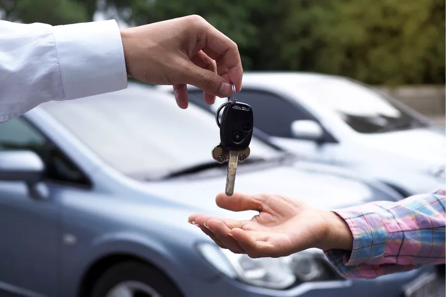 A picture of a person handling over car keys