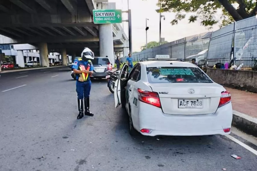 A picture of an enforcer issuing a ticket to a taxi.