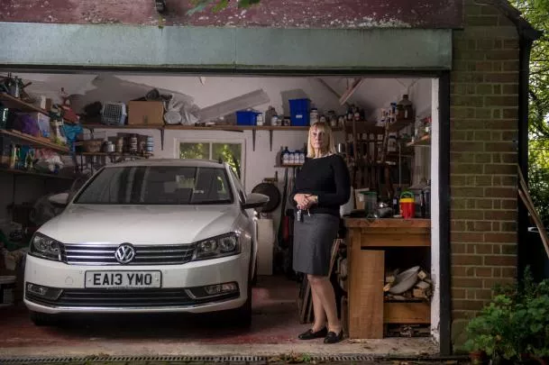 A woman standing next to a diesel Volkswagen in a garage