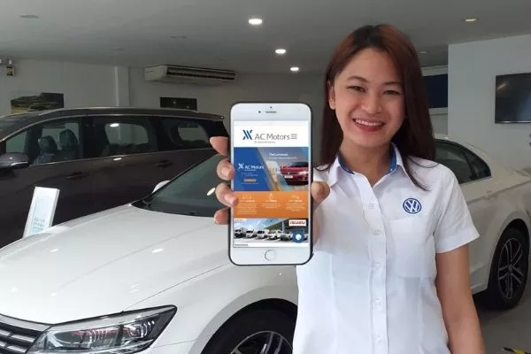 A saleslady holding a phone with the AC Motor webpage in it