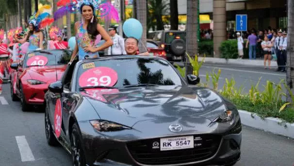 A beauty contestant standing in a mazda MX-5 smiles to the crowd at the 2017 Binibing Pilipinas pageant