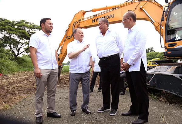 Four men standing and talking to each other in front of a crane