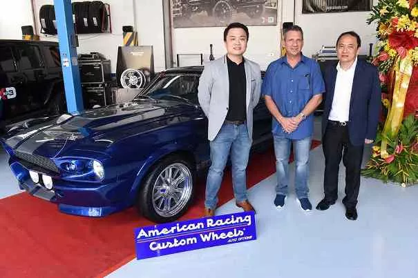 Three men standing beside a blue car at inauguration of Auto Options in Quezon City