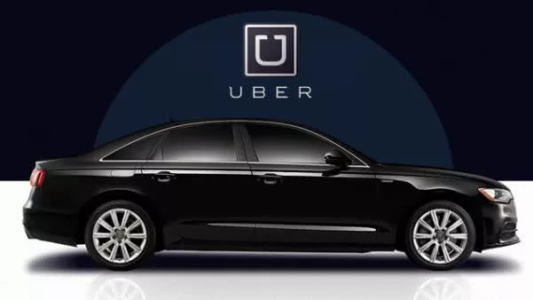 A black car in front of Uber backdrop