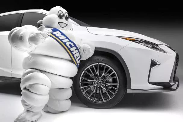 the Michelin Man standing next to a white car