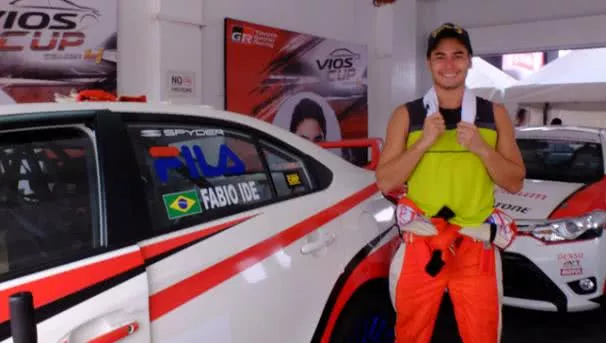 Handsome racer standing beside a racing car