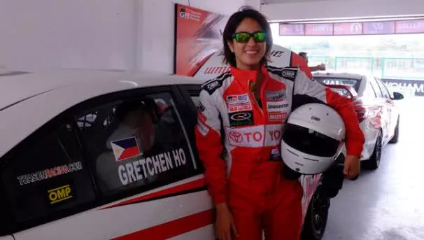 A woman in her racing suits holding her helmet