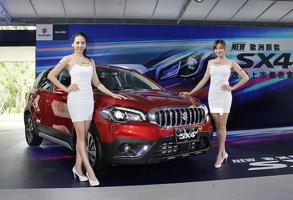 2 models posing beside a Suzuki SX4