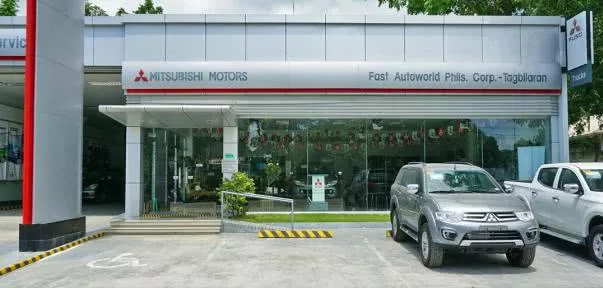 A silver SUV parking in front of a Mitsubishi dealership