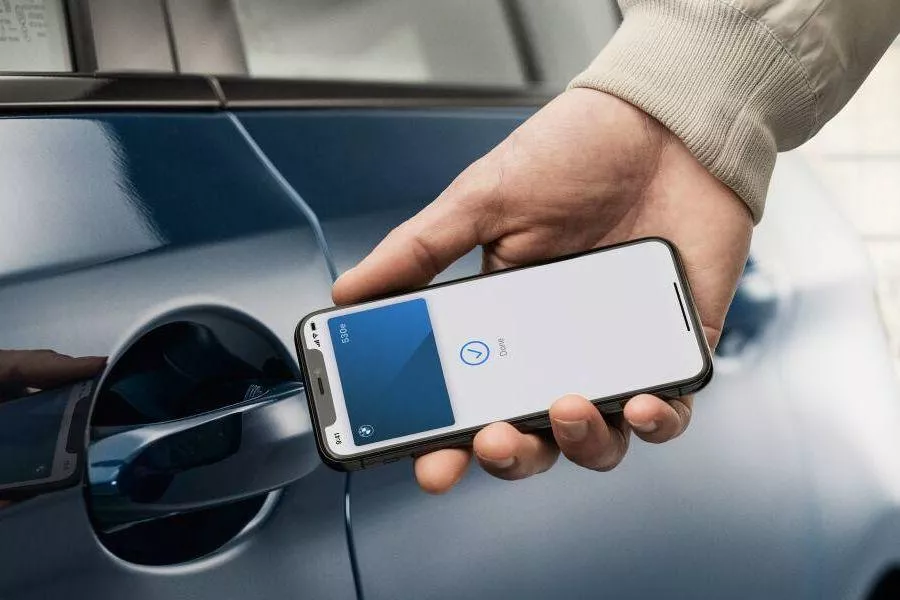 A closer picture of a person tapping his/her phone on a BMW's door handle