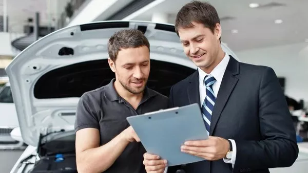 A car sales representative's job is to study and get trained about the new and in-stock vehicles Man talking to a car sales representative
