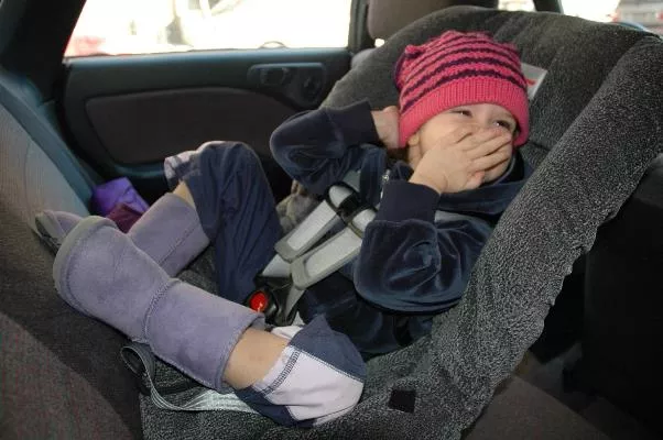 a kid sitting on a restraint device installed in a car