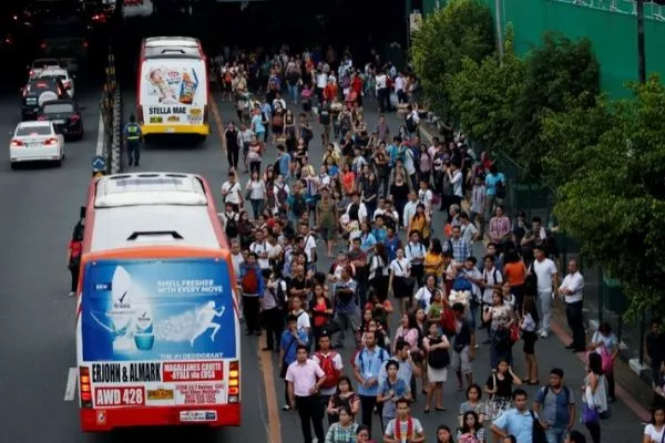 A picture of a crowd of people waiting for a bus