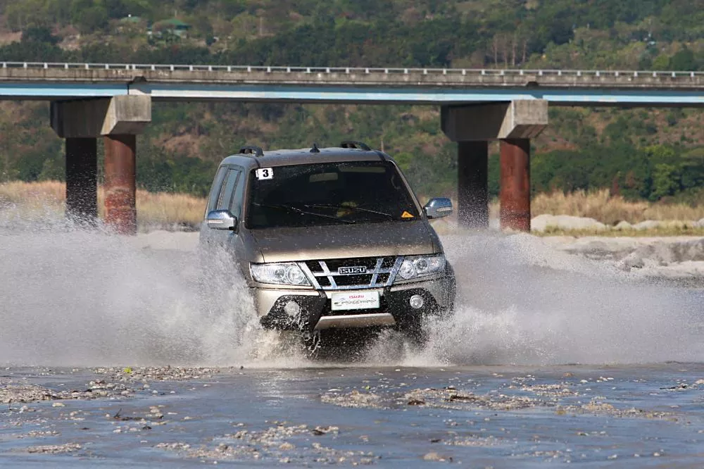 A golden Isuzu Crosswind traveling on the surface of water