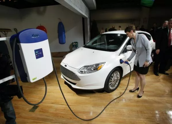 a woman is filling up the gas tank of a Ford Focus Electric