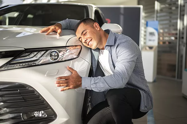 A picture of a man hugging a car.