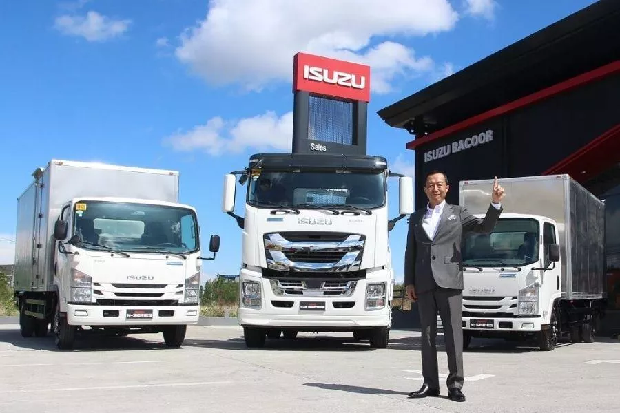 A picture of Hajime Koso with three Isuzu trucks in the background.