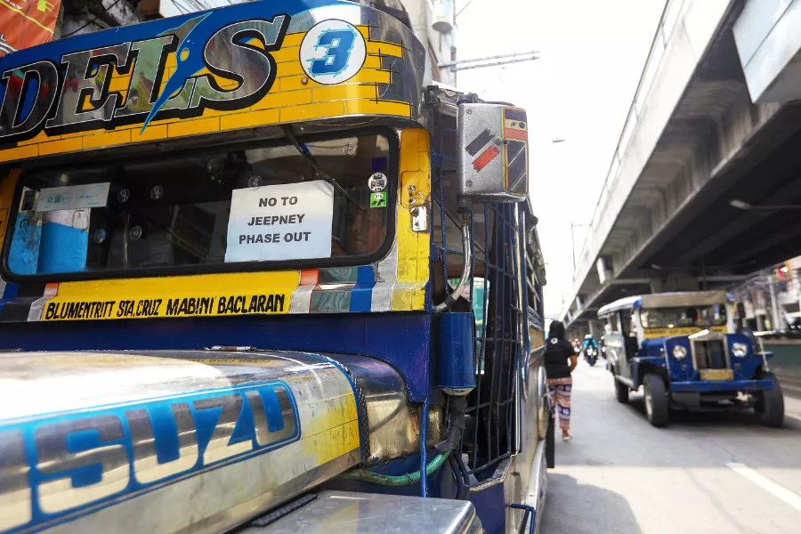 A picture of a jeepney with a poster protesting the jeepney modernization program.