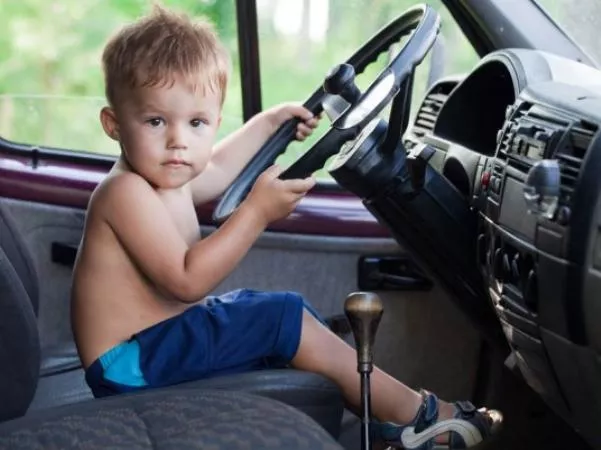 a kid seating behind the steering wheel