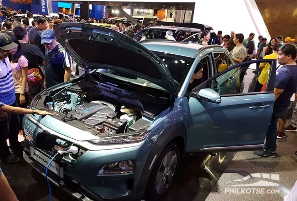 A picture of the Hyundai Kona Electric with an open hood and charger attached