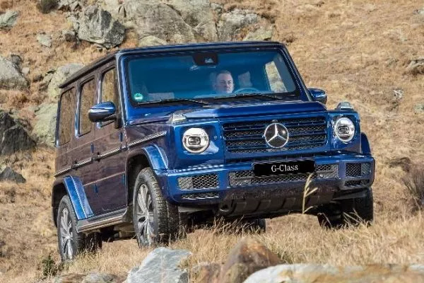 A blue G-Class climbing up a rocky hill