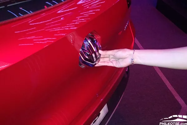 The shiny MG logo at the rear of the ZS functions as a latch that can open the trunk A shot of a person using the ZS logo latch to open the rear door