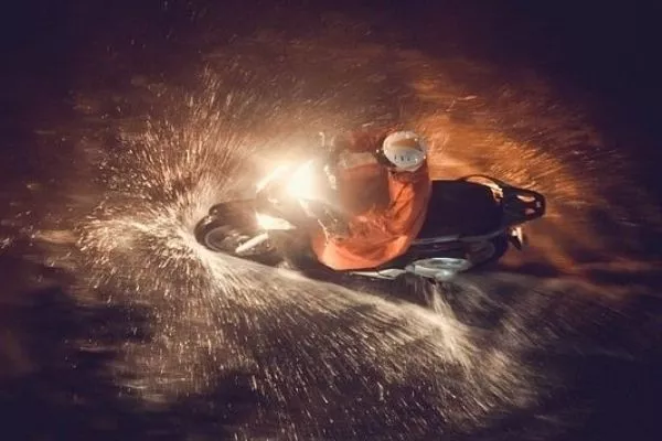 A picture of a man riding a motorcycle in the rain.