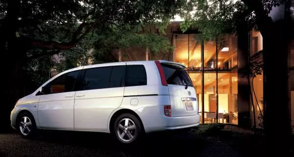 A white Toyota isis parking in front of a villa