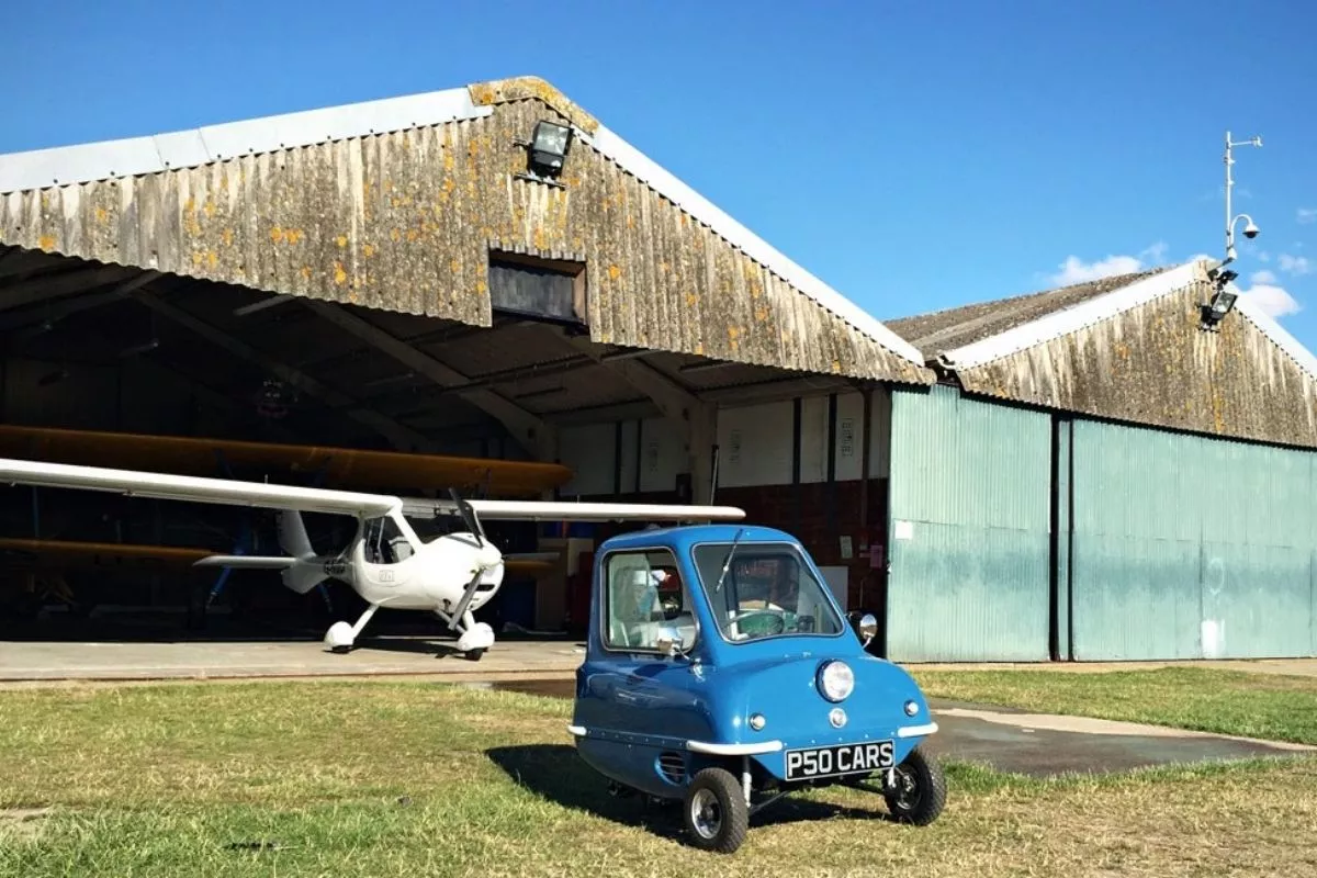 Peel P50 by a hangar