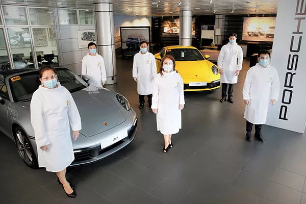 A picture of PGA Cars employees with Porsche models