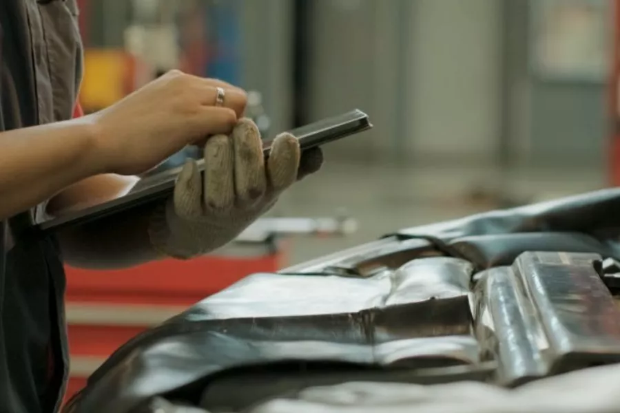 A picture of a person checking a car.