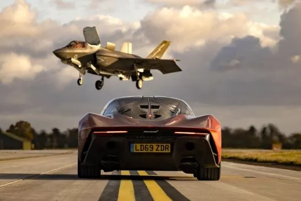 A picture of a McLaren Speedtail with an F-35 hovering in the background