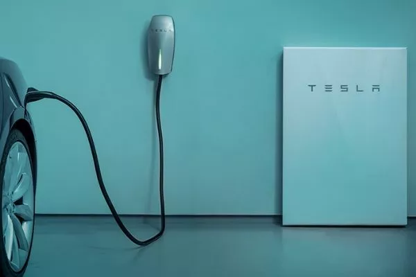 A picture of a Tesla EV charging at home