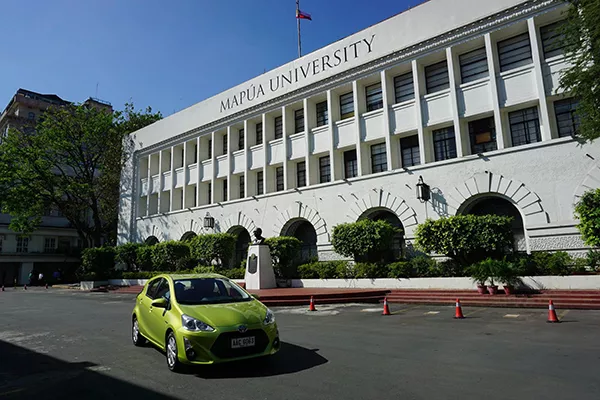 A picturesque scene of a Toyota Prius with a large campus building in the background