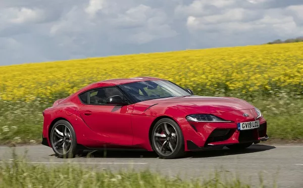 A picture of a red Toyota Supra on a country road