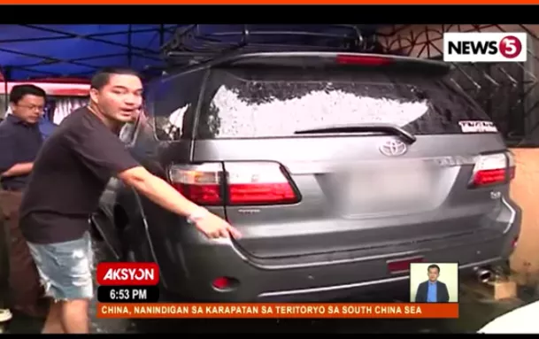 A man checking the back portion of his car