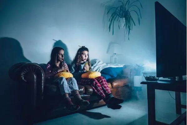 Two girls watching a tv at night