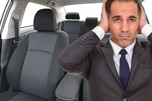 Man covering ears inside noisy car