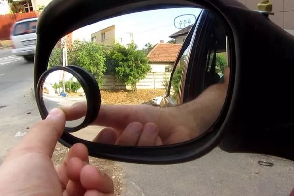A picture of a man adjusting side mirror