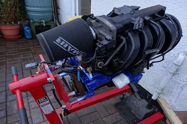 a v8 engine on an engine stand highlighting its aftermarket air filter.