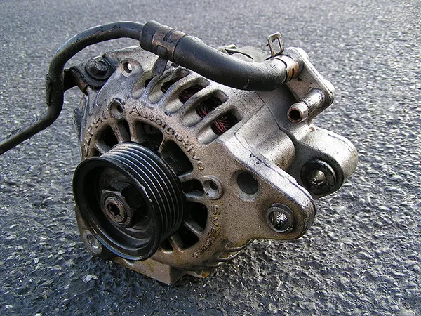 An alternator taken out from the engine bay and laid down on the street.