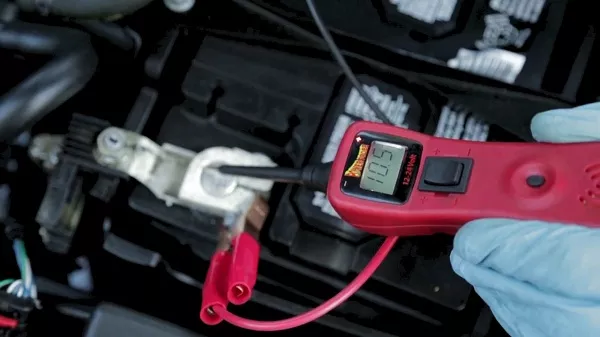 Check if the car battery is having trouble charging Man checking the voltage of the car battery