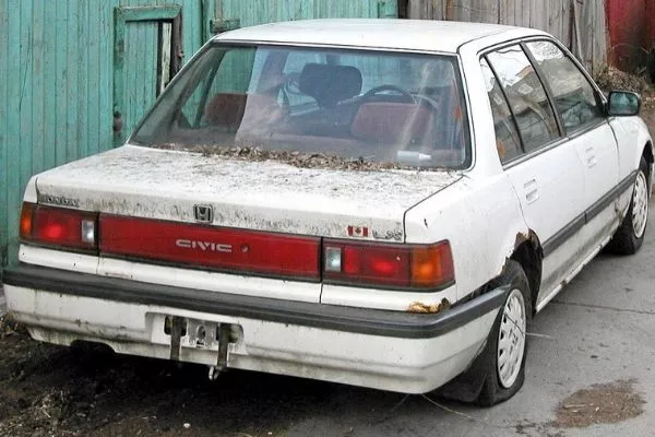 A picture of a white beater honda rotting in the garage