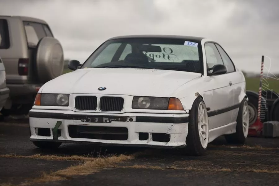 A picture of the a BMW E36 parked on a drift track's parking lot